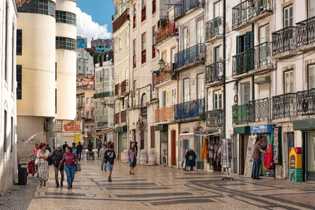A wide tiled street in Mouraria, Lisbon, with calçada pavement and azulejo façades