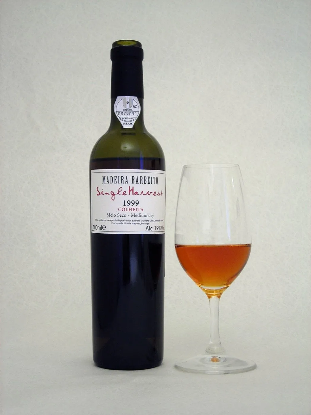 Bottle of Barbeito single harvest Madeira beside a tasting glass of amber wine