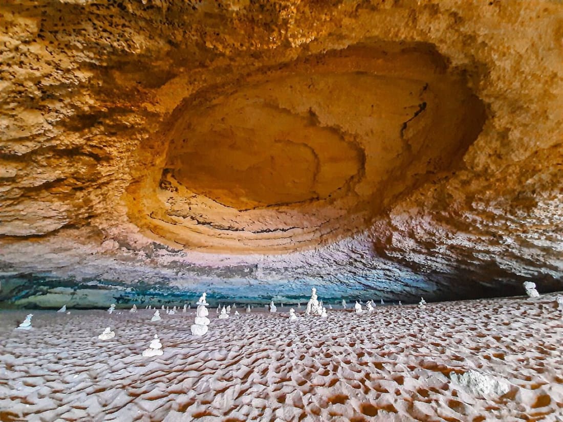 Inside the Benagil sea cave, the domed sandstone ceiling and sandy floor