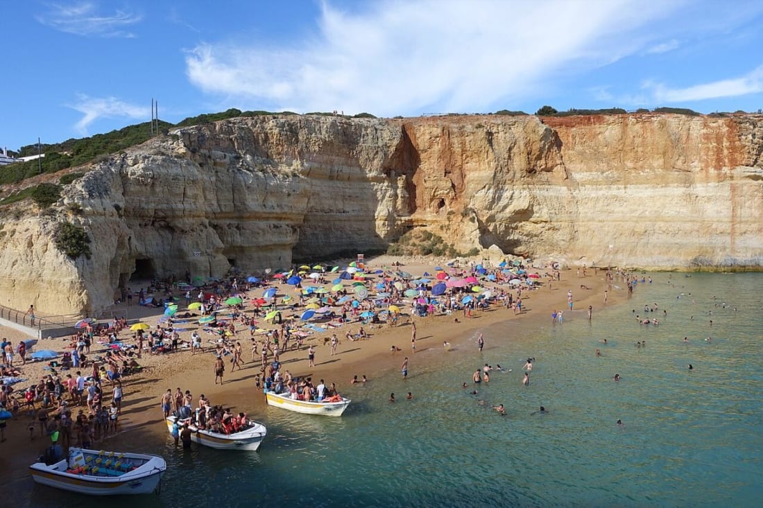 Praia de Benagil beach below golden cliffs, with tour boats on the water