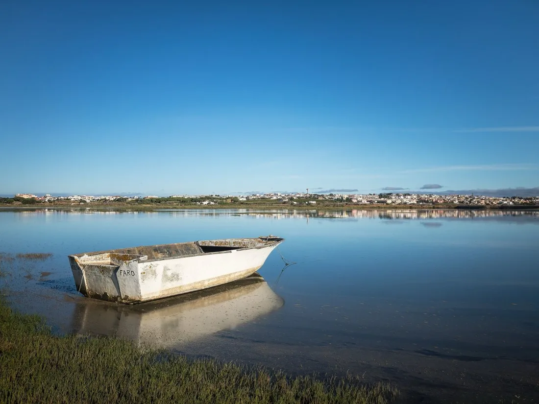 A small boat marked Faro moored in the calm Ria Formosa lagoon