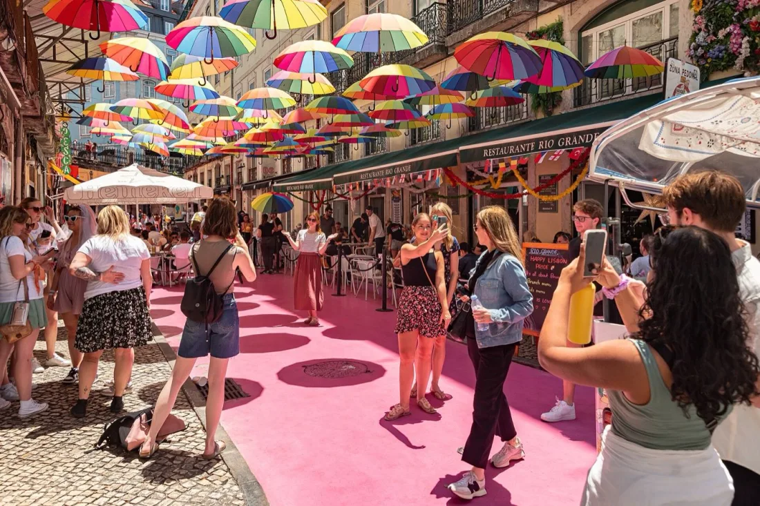 The colorful umbrellas and pink-painted street of Rua Nova do Carvalho in Cais do Sodré, Lisbon