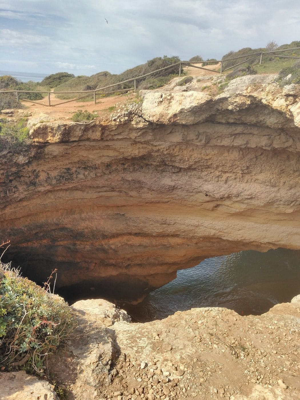 The fenced skylight of Benagil Cave beside the Seven Hanging Valleys Trail