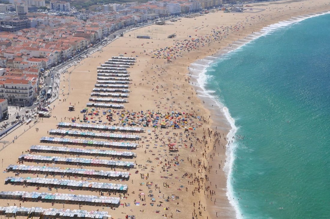 Summer rows of striped tents on Nazaré's town beach, Praia da Vila