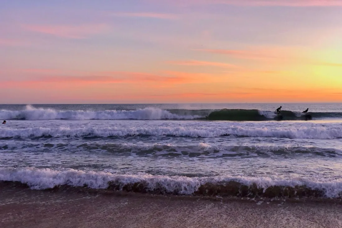 Surfers heading out at sunset on Praia de Carcavelos near Lisbon