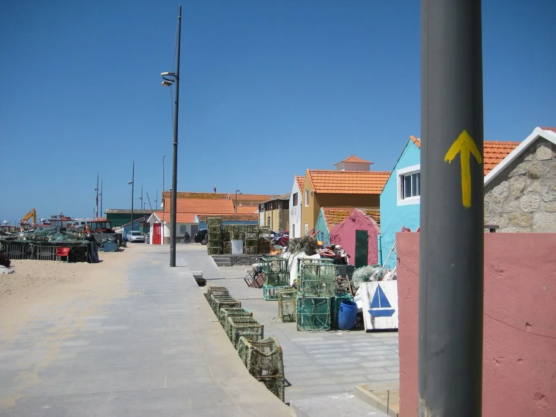 Yellow Camino arrow marking the Coastal route through a fishing village north of Porto