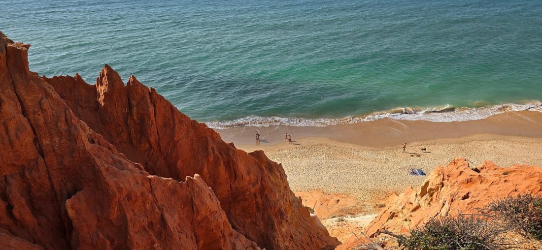 Red ochre cliffs above the pale sand and turquoise water of Praia da Falésia near Albufeira