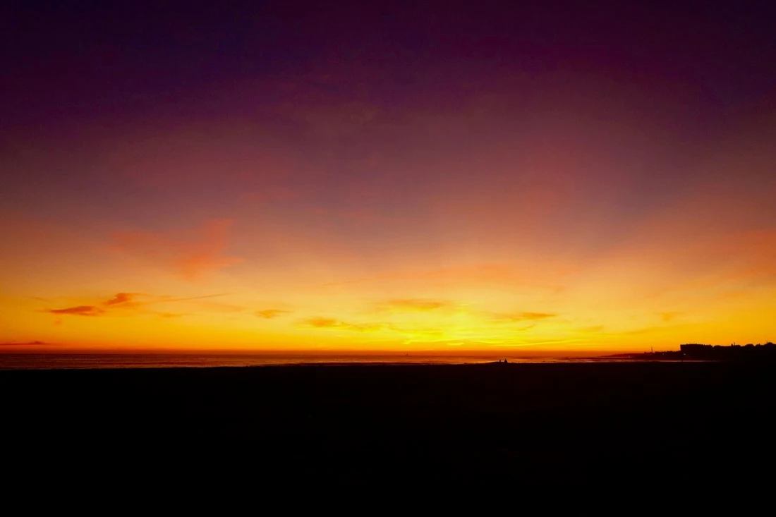 Orange and purple sunset over the empty sand at Praia de Carcavelos near Lisbon