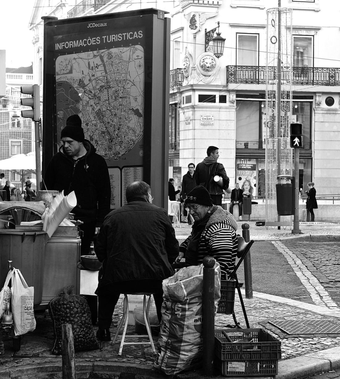 Street vendors roasting chestnuts over coals on a corner in Chiado, Lisbon